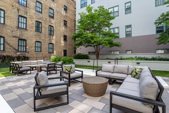 an outdoor patio area with couches and tables and a brick building  at The Cosmopolitan, St Paul